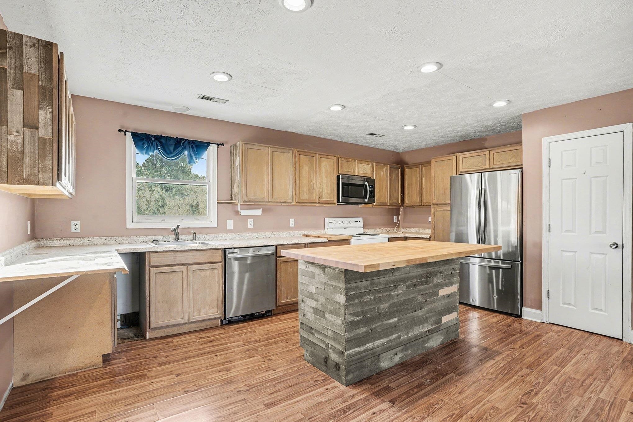 1897 Heritage Road Loris, SC 29569 - Photo 32 of 32 Kitchen featuring light countertops, stainless steel appliances, open floor plan, light wood-style floors, and a textured ceiling