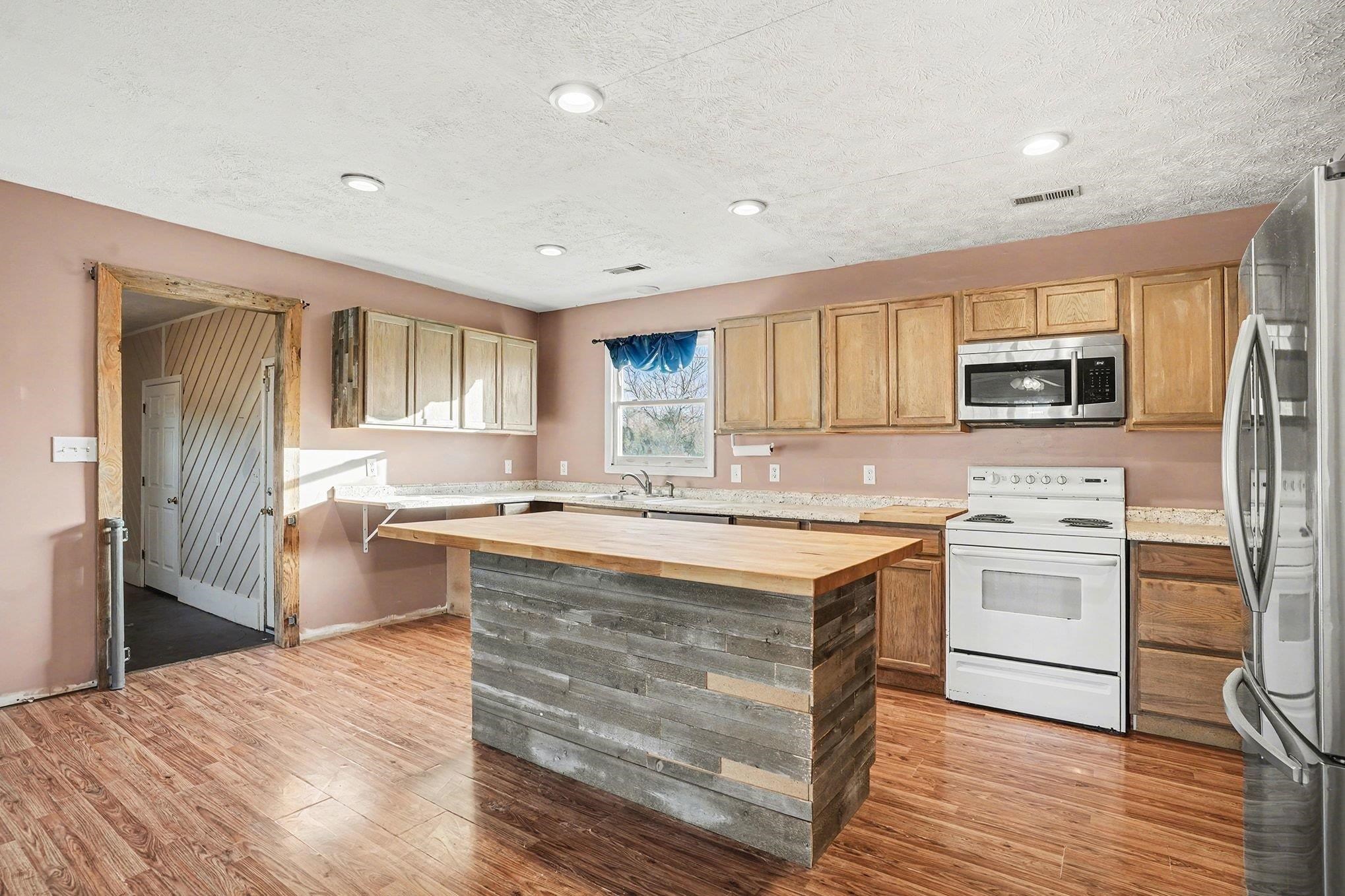 1897 Heritage Road Loris, SC 29569 - Photo 9 of 32 Kitchen featuring stainless steel appliances, butcher block counters, light wood-style floors, a kitchen island, and a textured ceiling