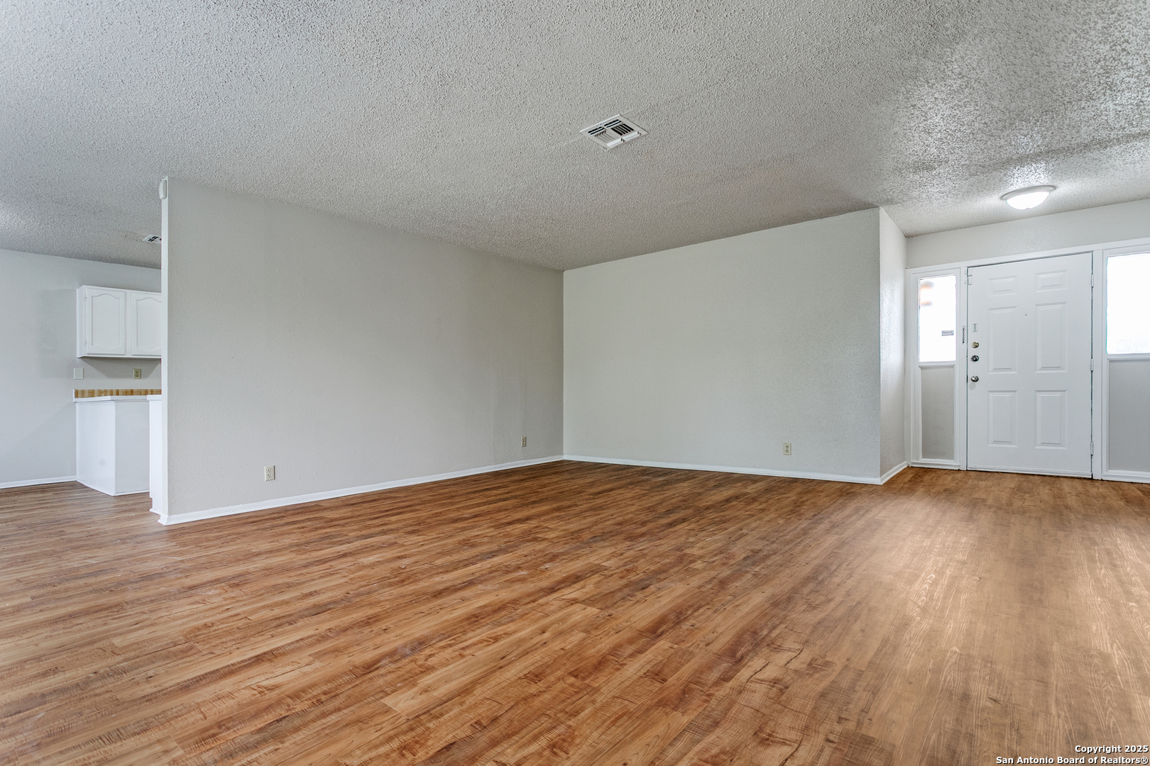 2803 Fred Haise Drive Kirby, TX 78219 - Photo 4 of 24 a view of an empty room with wooden floor and a window