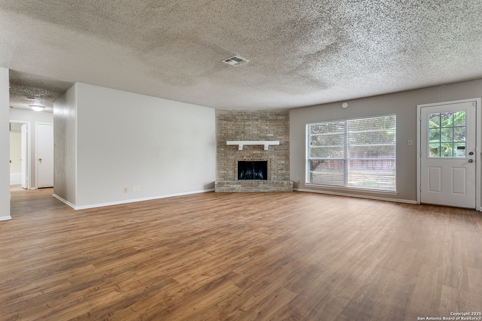 2803 Fred Haise Drive Kirby, TX 78219 - Photo 6 of 24 an empty room with wooden floor cabinet and windows