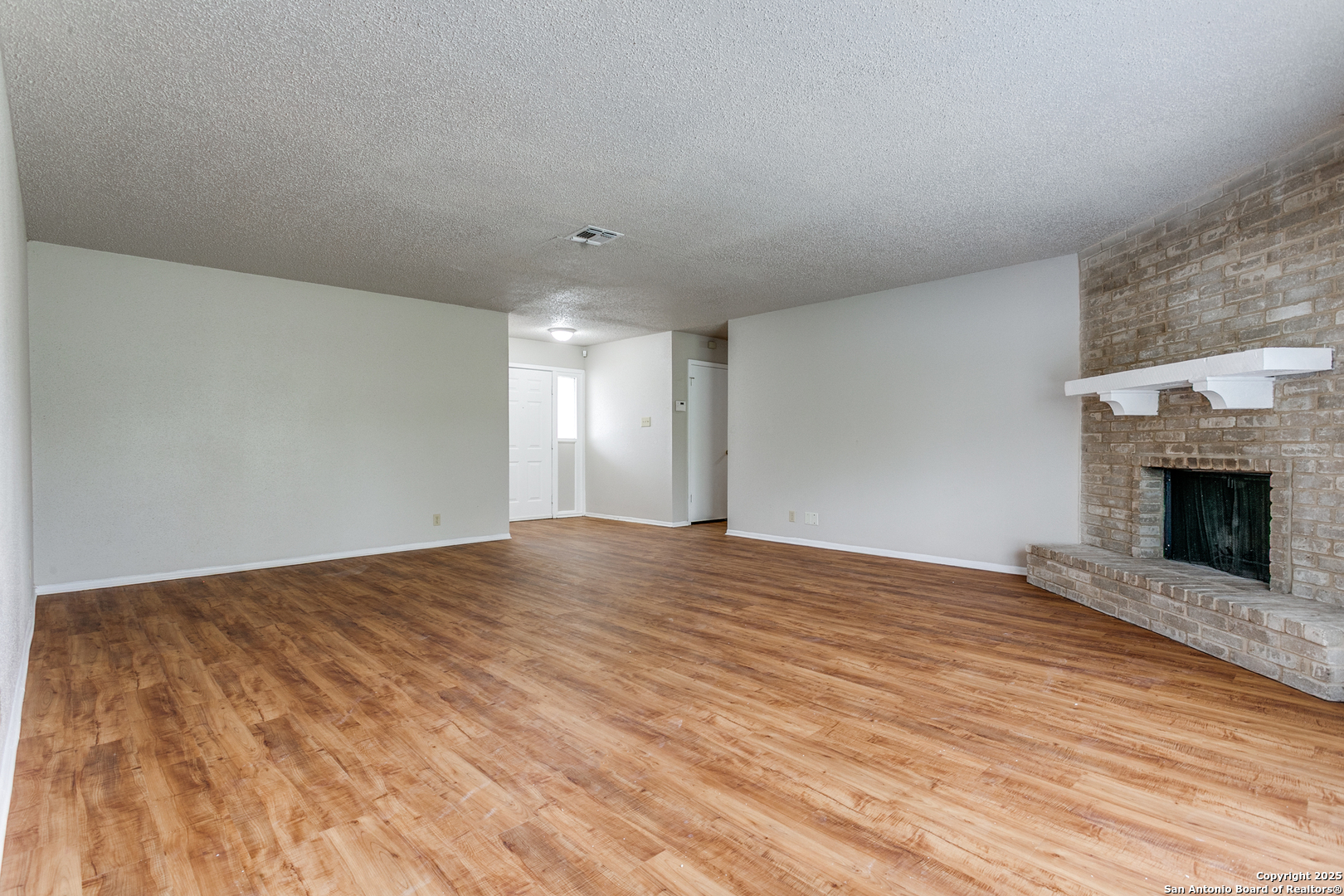 2803 Fred Haise Drive Kirby, TX 78219 - Photo 7 of 24 a view of empty room with wooden floor and fireplace
