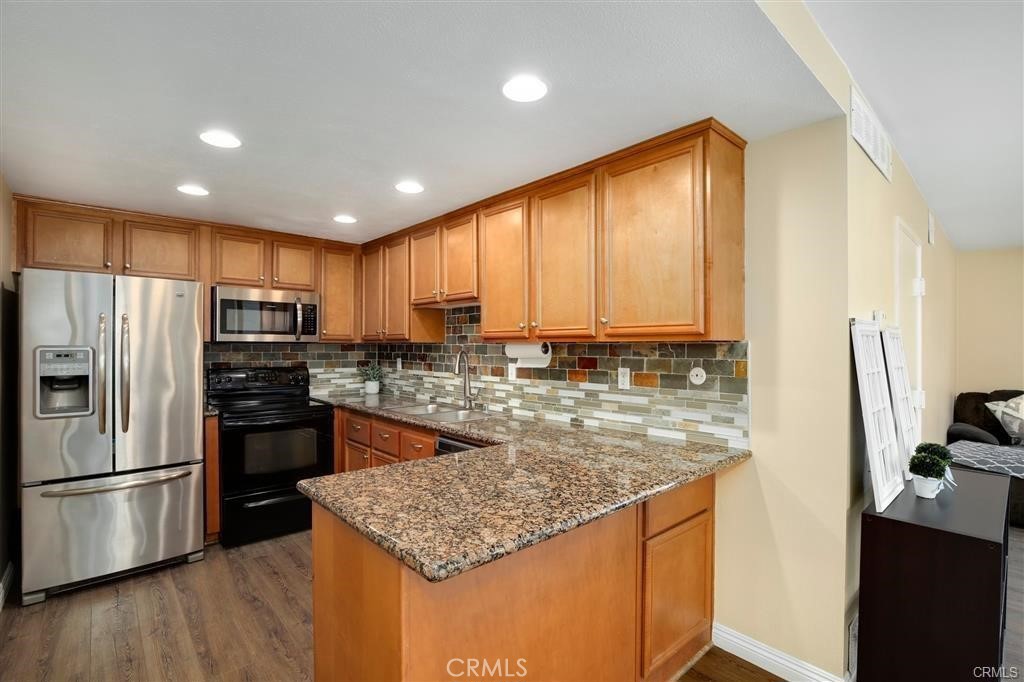 31909 Del Cielo, Unit 11 Bonsall, CA 92003 - Photo 5 of 16 a kitchen with stainless steel appliances granite countertop a refrigerator a stove and a sink with wooden floor