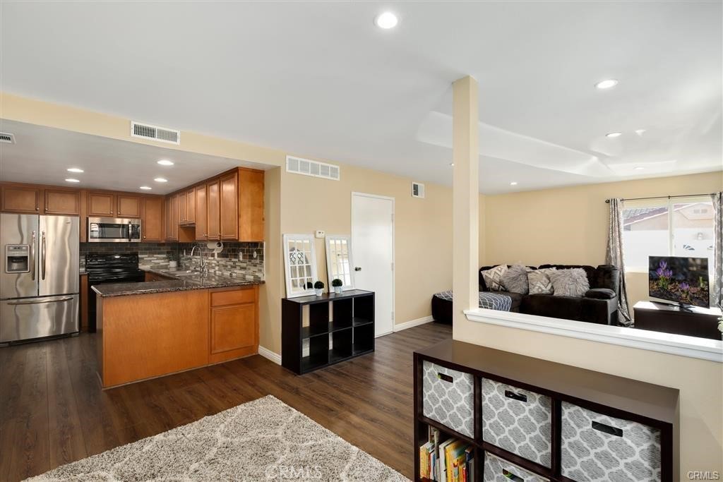 31909 Del Cielo, Unit 11 Bonsall, CA 92003 - Photo 7 of 16 a living room with stainless steel appliances kitchen island granite countertop a refrigerator a stove a sink dishwasher and white cabinets with wooden floor