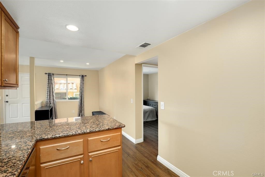 31909 Del Cielo, Unit 11 Bonsall, CA 92003 - Photo 8 of 16 a hallway with granite countertop white cabinets and wooden floor