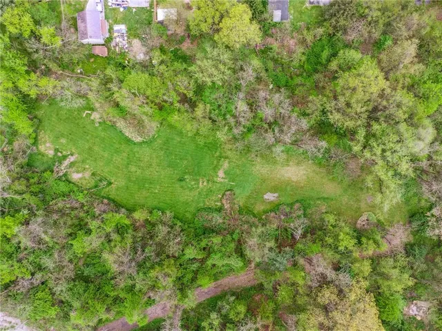 an aerial view of residential houses with outdoor space and trees