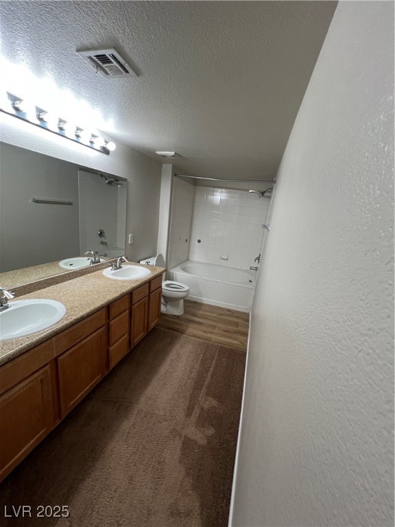7255 West Sunset Road, Unit 2072 Las Vegas, NV 89113 - Photo 10 of 19 Bathroom featuring double vanity, tub / shower combination, a textured ceiling, a textured wall, and dark wood-style floors