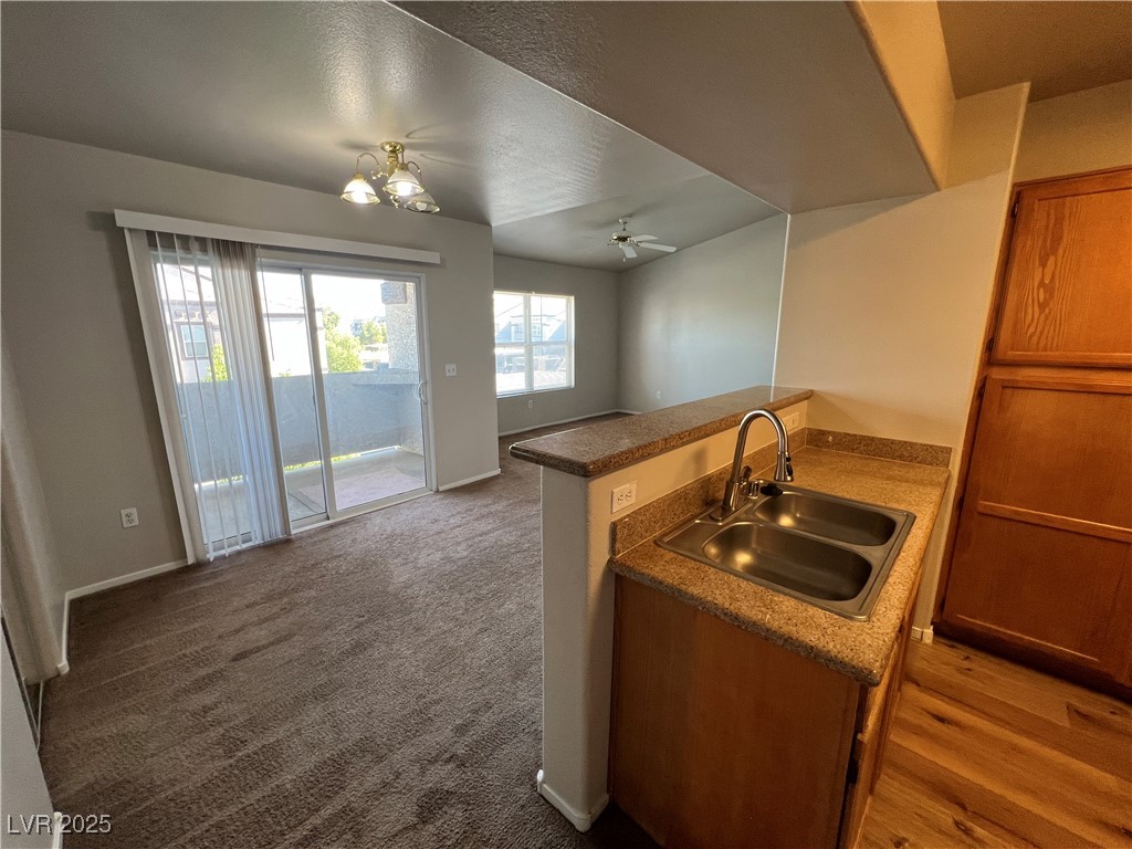 7255 West Sunset Road, Unit 2072 Las Vegas, NV 89113 - Photo 19 of 19 Kitchen featuring brown cabinetry, open floor plan, a peninsula, a ceiling fan, and dark carpet