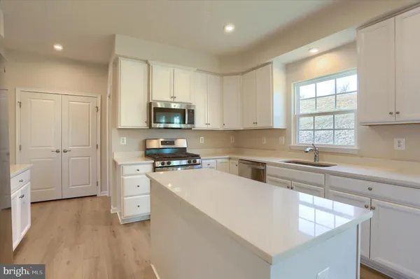 a kitchen with a sink a stove a refrigerator and white cabinets