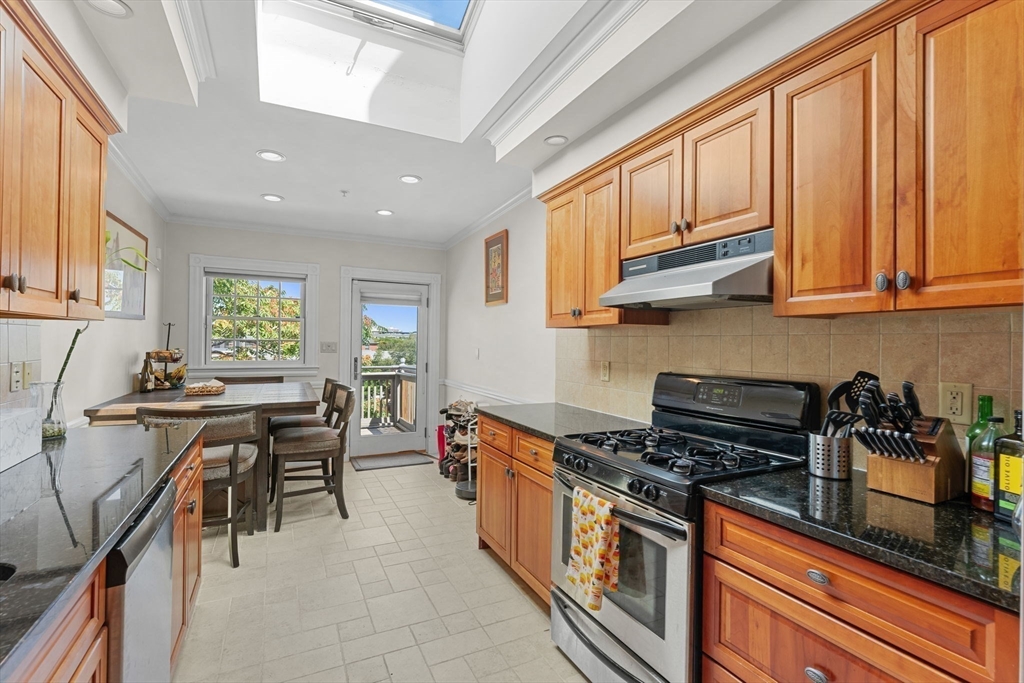 262-264 West Broadway Boston, MA 02127 - Photo 7 of 22 a kitchen with stainless steel appliances granite countertop a stove top oven a sink dishwasher and cabinets with wooden floor