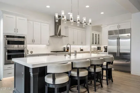 a kitchen with kitchen island a dining table chairs stainless steel appliances and cabinets