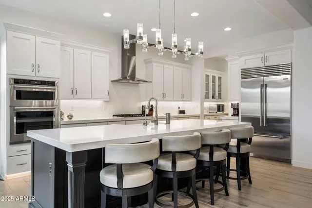 a kitchen with kitchen island a dining table chairs stainless steel appliances and cabinets