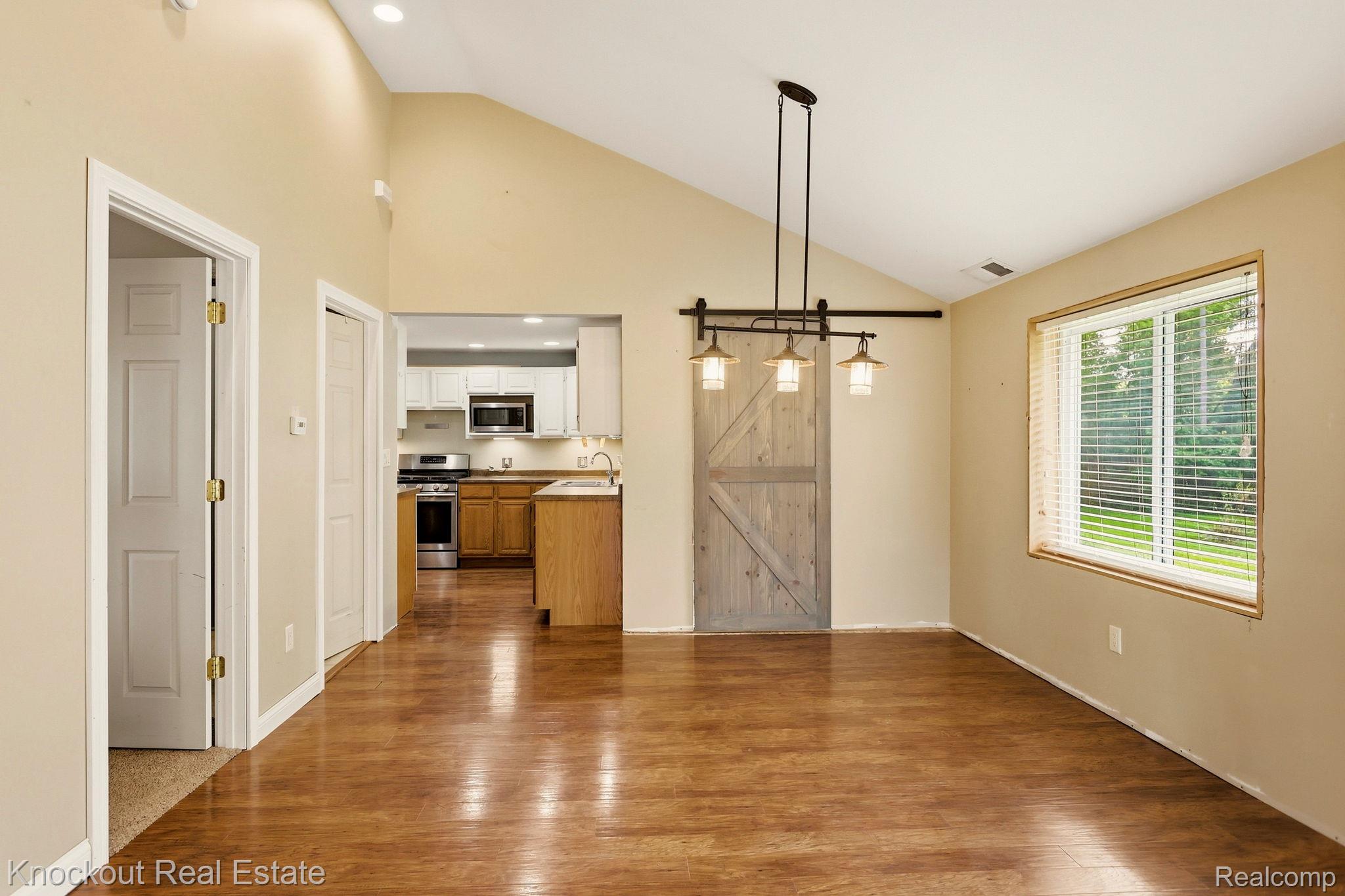 8811 Van Cleve Road Vassar, MI 48768 - Photo 11 of 39 Vaulted ceiling with recessed lighting, wood-finish flooring, and a modern sliding barn door