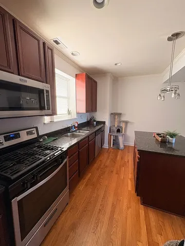 a kitchen with stainless steel appliances wooden floor sink stove microwave and cabinets