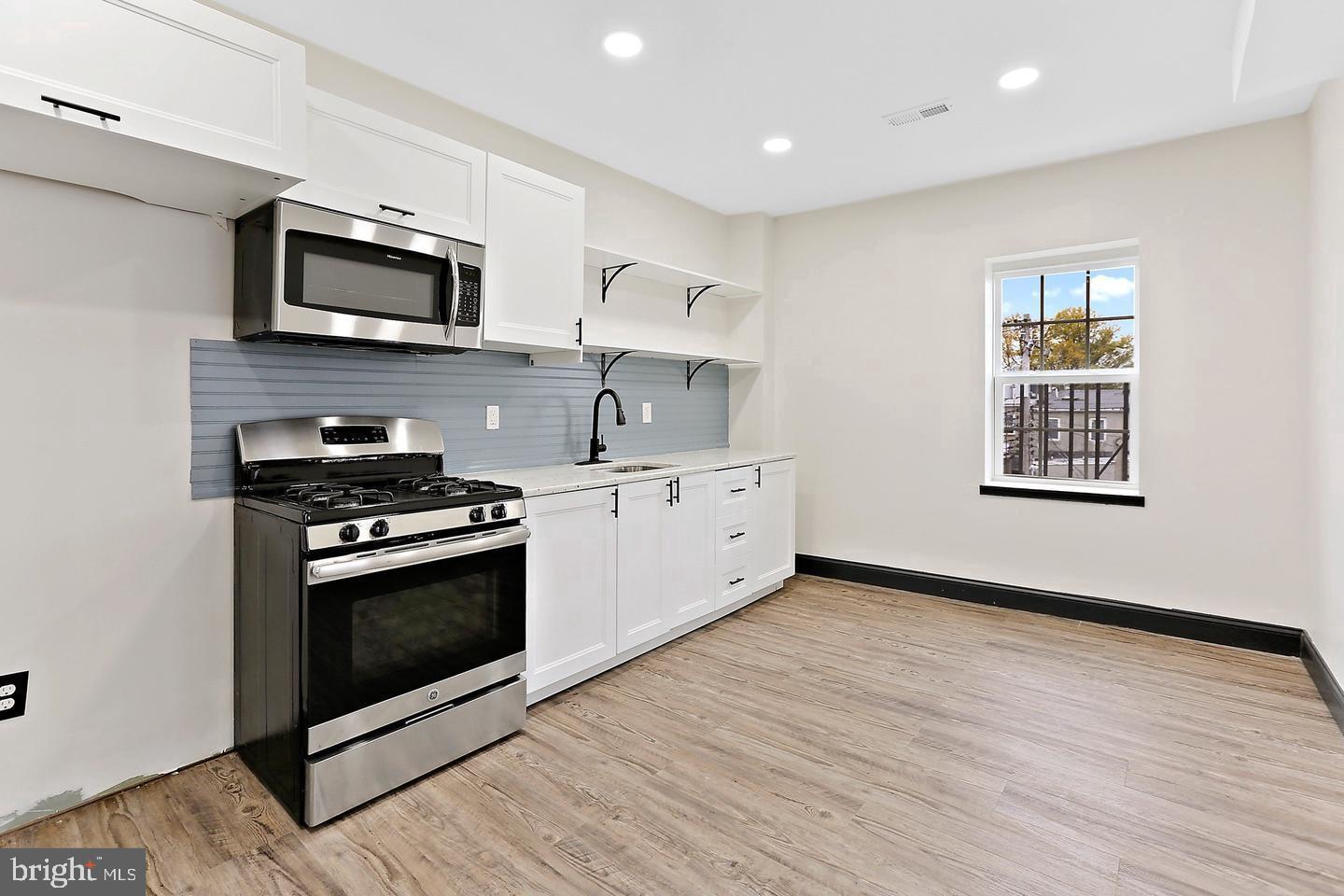 1732 McCulloh Street Baltimore, MD 21217 - Photo 24 of 30 a kitchen with stainless steel appliances granite countertop a stove a microwave and white cabinets