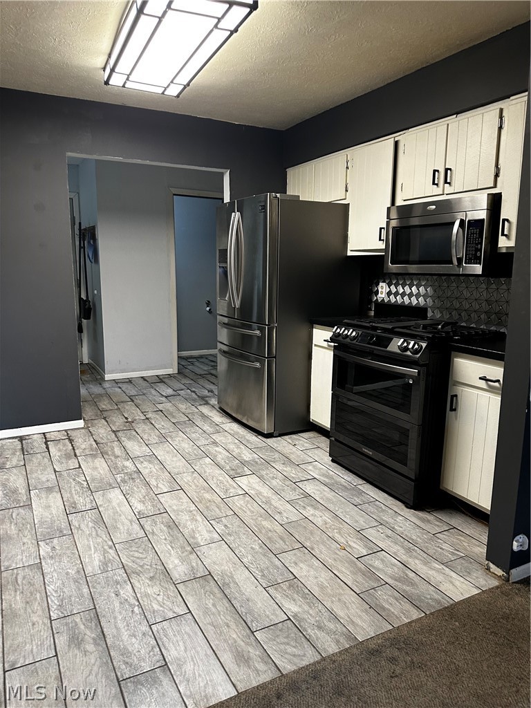 198 Park Road Painesville, OH 44077 - Photo 11 of 31 Kitchen featuring wood-finish tile flooring, white cabinetry, and stainless steel appliances