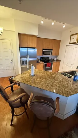 a kitchen with stainless steel appliances kitchen island granite countertop a sink and a white cabinets