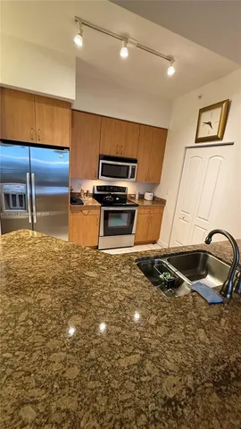 a kitchen with kitchen island granite countertop a stove and a sink