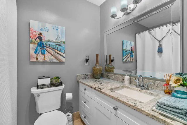 a bathroom with a granite countertop toilet sink and mirror
