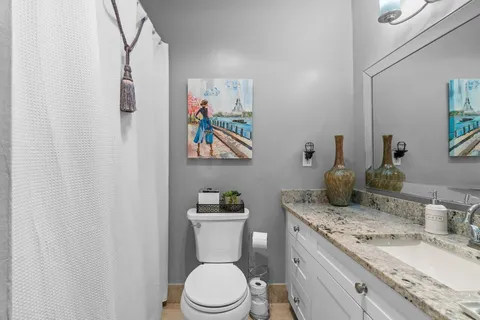 a bathroom with a granite countertop sink mirror vanity and toilet