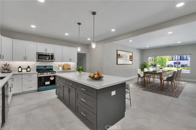 a kitchen with stainless steel appliances kitchen island granite countertop a stove top oven a sink a dining table and chairs