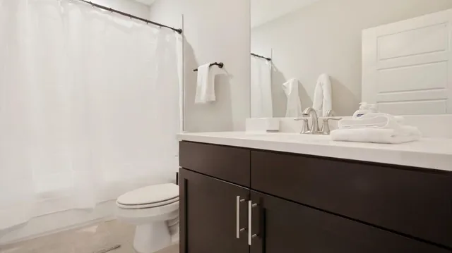 a view of a white house with a small yard and large trees