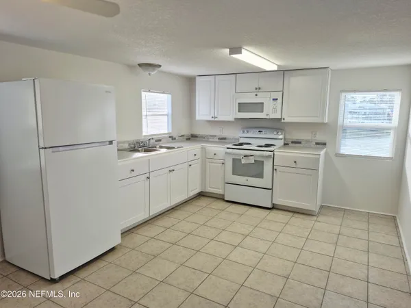 a kitchen with white cabinets a sink a stove a refrigerator and white cabinets