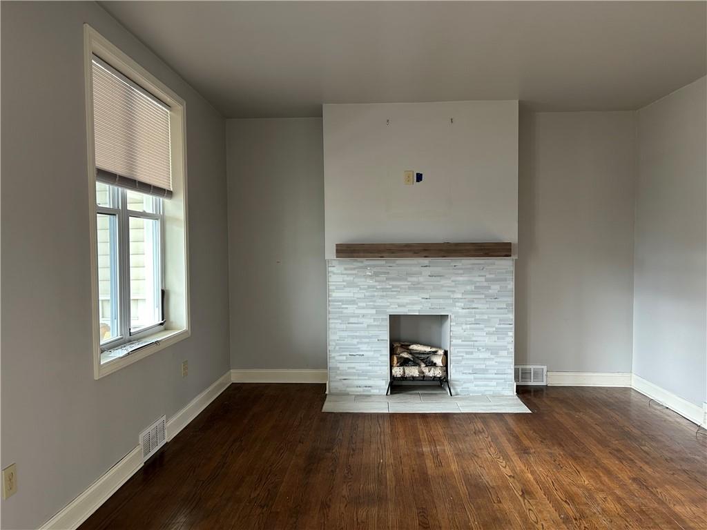 217 Arthur Street, Unit 1 Zelienople, PA 16063 - Photo 3 of 13 an empty room with wooden floor fireplace and windows