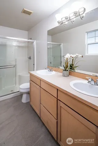 a bathroom with a granite countertop sink a toilet a mirror and shower