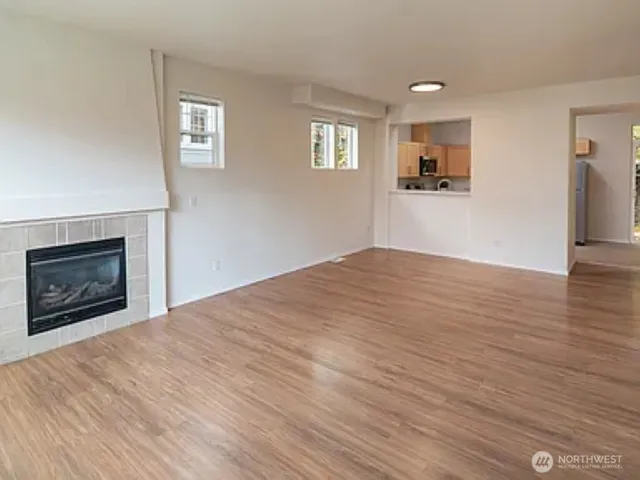 a big room with wooden floor a fireplace and windows