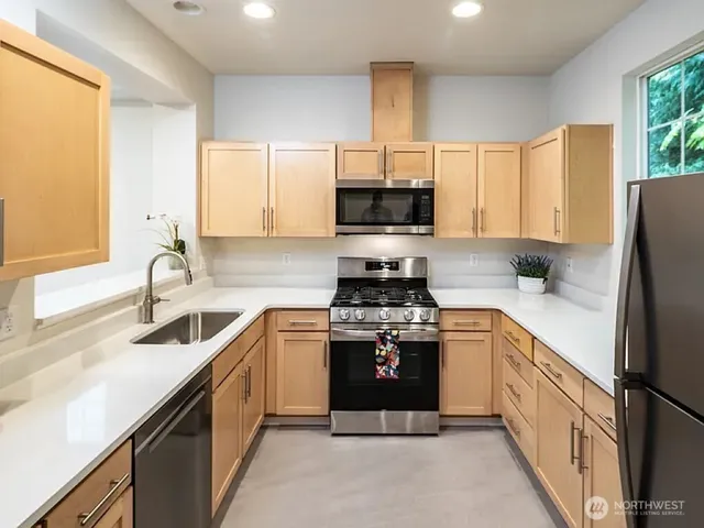 a kitchen with stainless steel appliances a sink stove refrigerator and a window