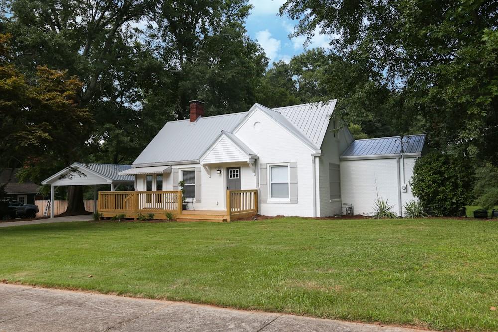 222 Mill Street Bowdon, GA 30108 - Photo 1 of 1 a view of a white house that has a big yard with table and chairs under an umbrella