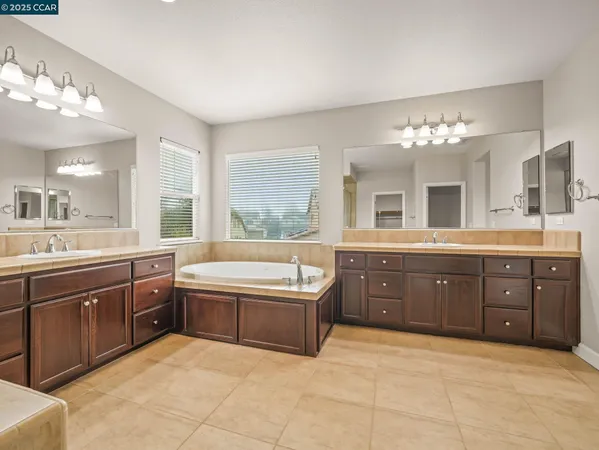 a spacious bathroom with a granite countertop double vanity sink a bathtub and a mirror