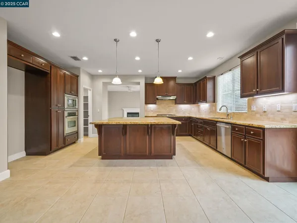 a large kitchen with stainless steel appliances granite countertop a large counter top a refrigerator and a sink