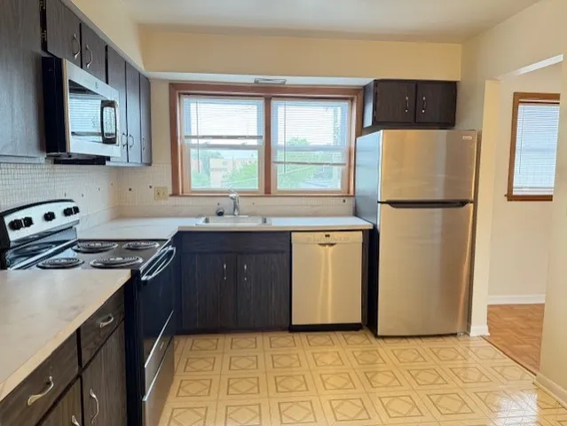a kitchen with a sink a refrigerator and a stove top oven