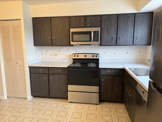 a kitchen with stainless steel appliances granite countertop wooden cabinets a stove top oven a sink and dishwasher