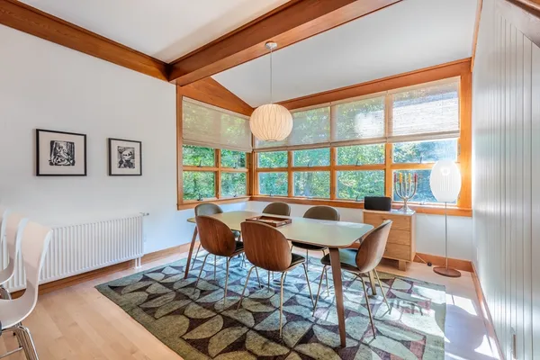 a dining room with furniture a large window and wooden floor
