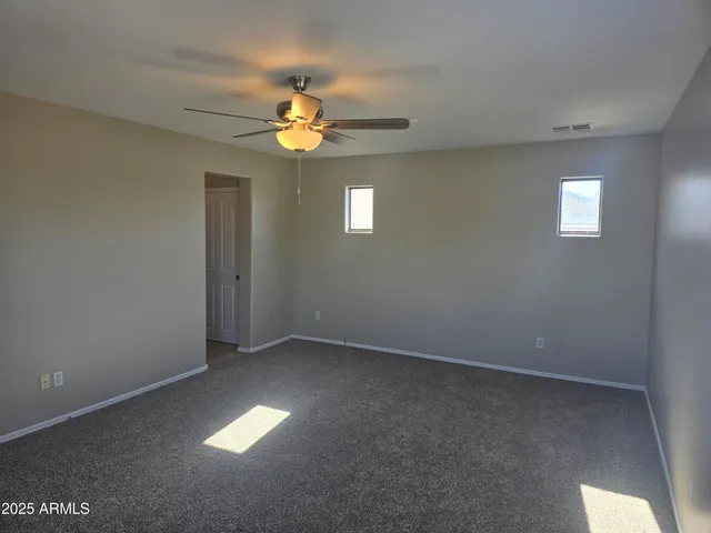 an empty room with a window and chandelier fan
