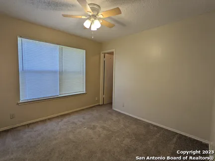 an empty room with windows and fan