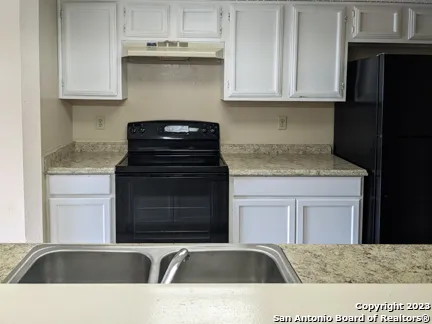 a kitchen with granite countertop a sink dishwasher a stove and black cabinets