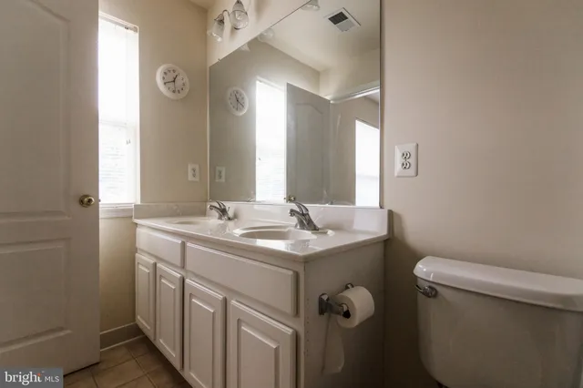 a bathroom with a granite countertop toilet a sink and a mirror