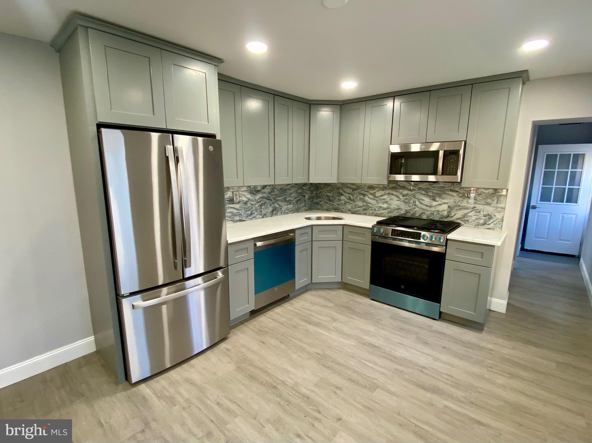4404 Leiper Street Philadelphia, PA 19124 - Photo 6 of 14 a kitchen with stainless steel appliances granite countertop a refrigerator stove and wooden floor
