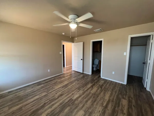 an empty room with wooden floor and ceiling fan