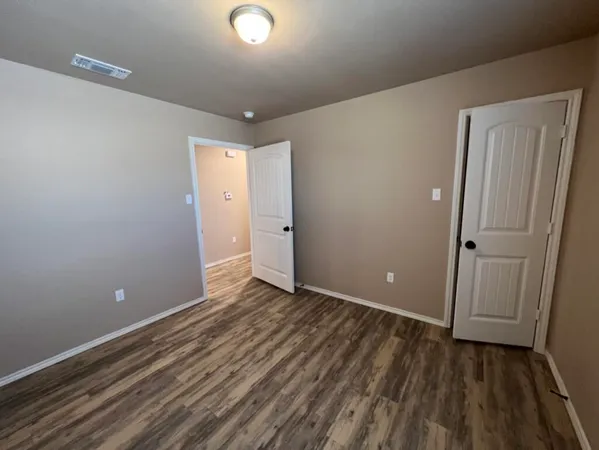 a view of an empty room with wooden floor and closet