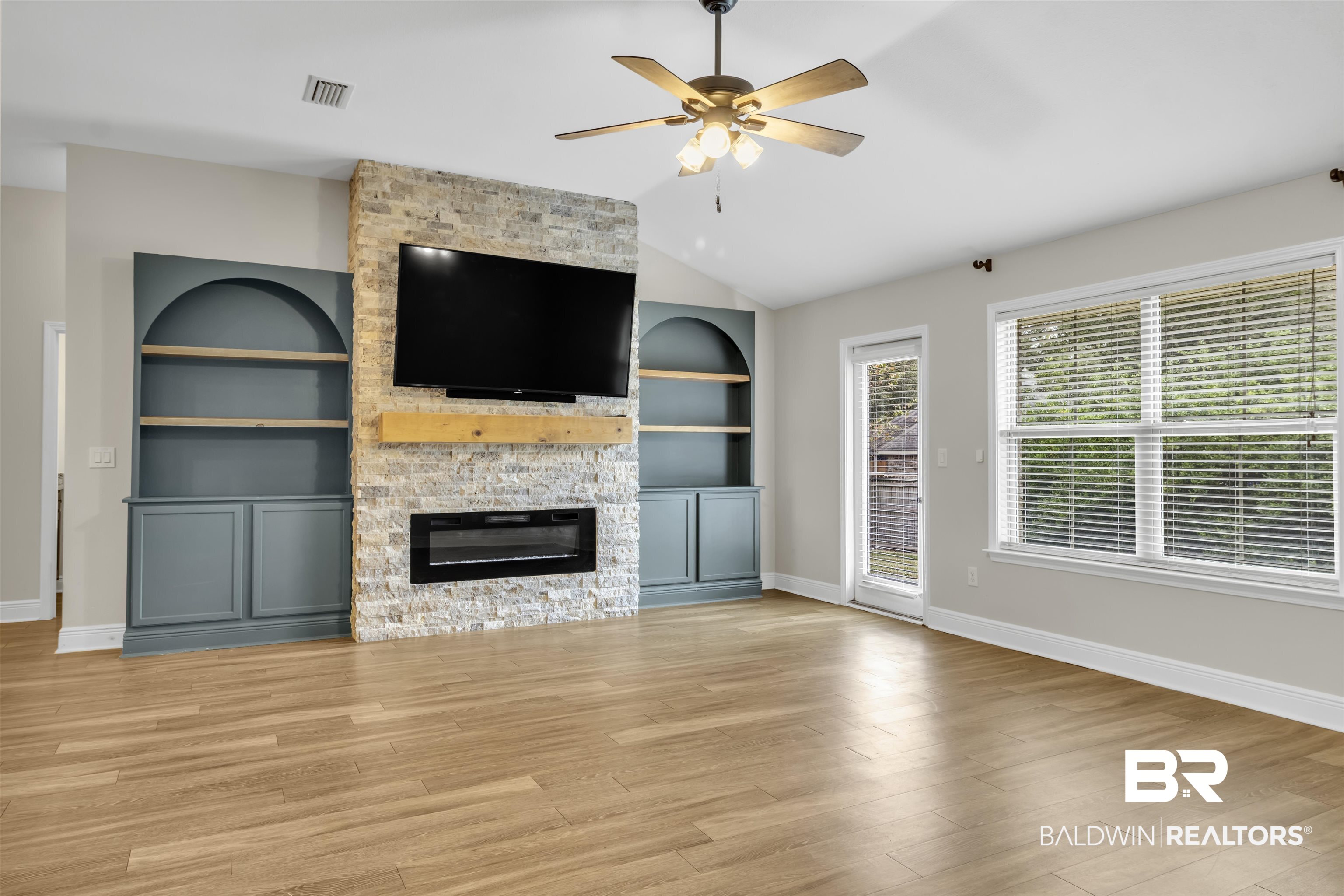 13166 Hulbert Court Foley, AL 36535 - Photo 9 of 27 Unfurnished living room featuring built in shelves, a fireplace, vaulted ceiling, light wood-style flooring, and ceiling fan
