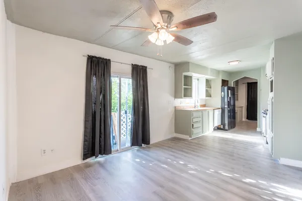 a view of a big room with wooden floor and a kitchen