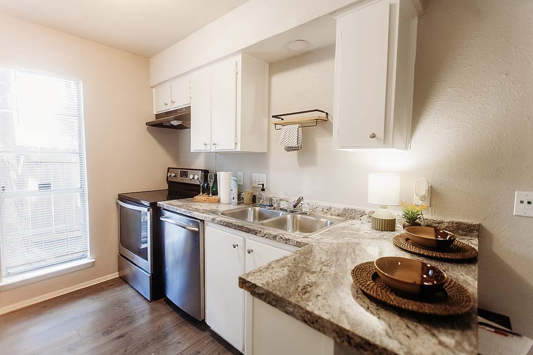 3712 Menchaca Road, Unit 7 Austin, TX 78704 - Photo 3 of 13 Granite counters and white cabinetry define this functional kitchen space with durable wood-look flooring.