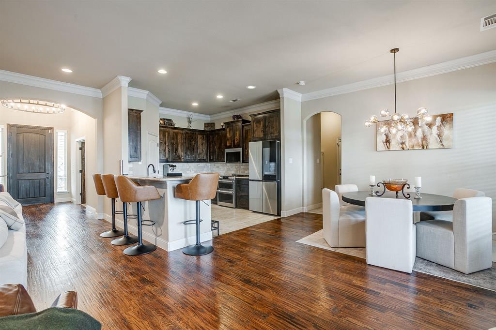 7320 Spring Ranch Court Godley, TX 76044 - Photo 22 of 40 a kitchen with stainless steel appliances granite countertop a refrigerator a stove top oven a dining table and chairs with wooden floor