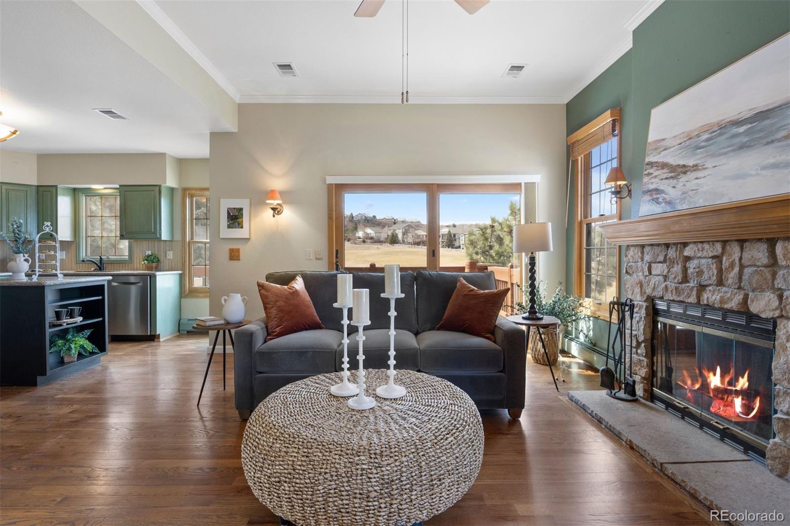 10 Roder Gate Lane Castle Pines, CO 80108 - Photo 11 of 32 a living room with furniture a fireplace and a floor to ceiling window