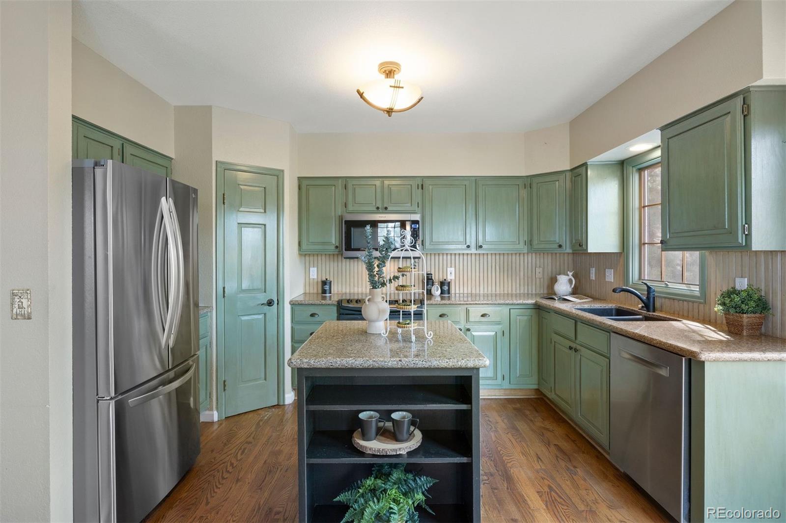 10 Roder Gate Lane Castle Pines, CO 80108 - Photo 12 of 32 a kitchen with kitchen island a sink stainless steel appliances and cabinets