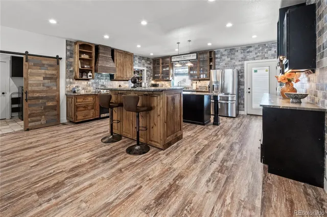 a kitchen with stainless steel appliances wooden floor a refrigerator and a stove top oven